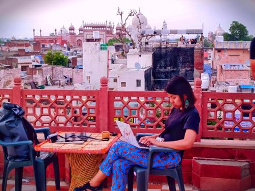 een vrouw aan een tafel die een krant leest bij Hotel India inn in Agra