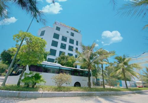 einem weißen Bus, der vor einem Gebäude parkt in der Unterkunft Tuấn Đạt Luxury FLC Sầm Sơn in Sầm Sơn