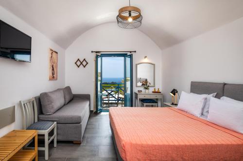 a bedroom with a bed and a couch and a window at Kalimera Hotel in Akrotiri