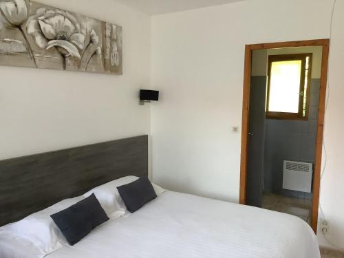 a bedroom with a white bed and a painting on the wall at la dolce farniente in Biaudos