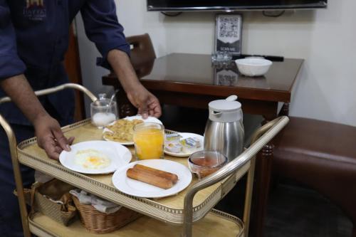 a man standing in front of a tray of breakfast food at Hayyat Luxury Hotel Apartments in Lahore