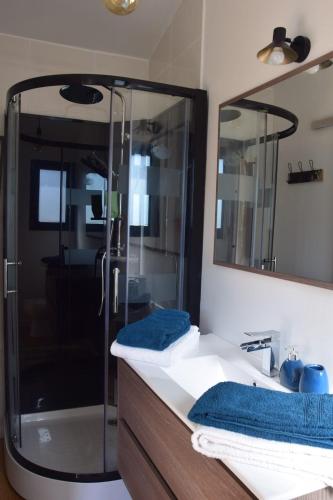 y baño con ducha y lavabo con toallas azules. en Chambre d’hôte indépendante, en Lacanau