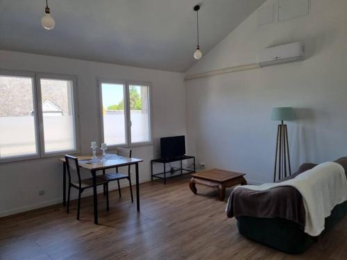 ein Wohnzimmer mit einem Tisch und einem Sofa in der Unterkunft Grand appartement, lumineux in Miniac-Morvan