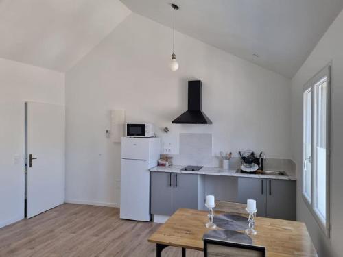eine Küche mit einem Holztisch und einem weißen Kühlschrank in der Unterkunft Grand appartement, lumineux in Miniac-Morvan