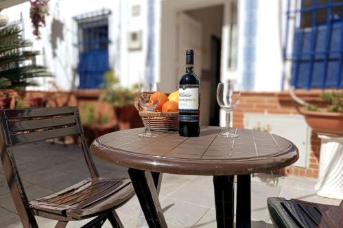 una botella de vino sentada en una mesa con una cesta de fruta en Típico y pintoresco patio de vecinos, con encanto, en Sevilla