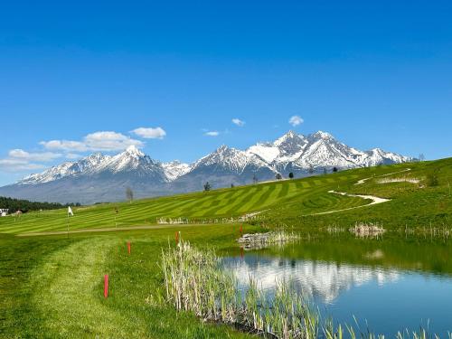 a golf course with a lake and snow covered mountains at Royal Village - Royal Views apartments in Malý Slavkov
