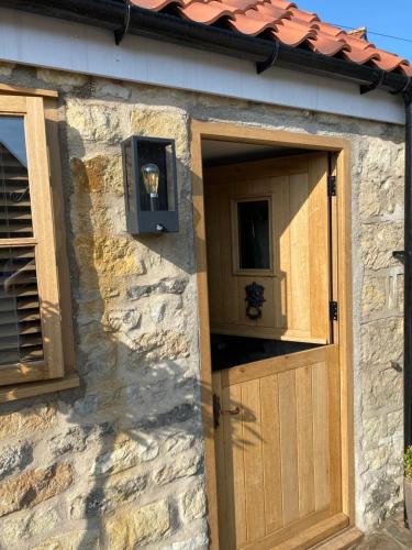 a stone house with a wooden door and a window at Cornerstone House in Pickering