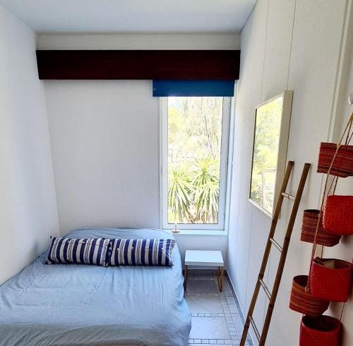 a small bedroom with a bed and a window at SUPERBE APPARTEMENT DANS CADRE D'EXCEPTION - Piscine, Plage et Tennis privé in Bandol