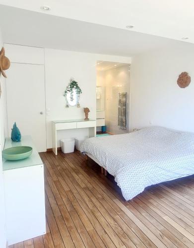 une chambre blanche avec un lit et un parquet dans l'établissement SUPERBE APPARTEMENT DANS CADRE D'EXCEPTION - Piscine, Plage et Tennis privé, à Bandol