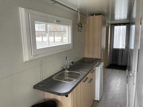 una pequeña cocina con fregadero y ventana en Houseboot Kingfisher, lake view, en Biddinghuizen