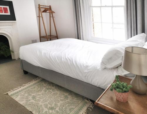 a bedroom with a bed with white sheets and a window at Luminous Town house by the sea in Kent