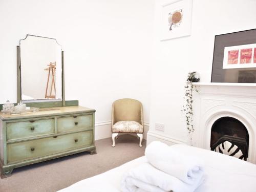 a bedroom with a dresser and a mirror and a fireplace at Luminous Town house by the sea in Kent