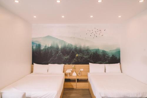 two beds in a room with a painting on the wall at Hang Mua Boutique in Ninh Binh