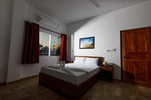 a bedroom with a bed and a window with red curtains at Pearl Island Inn in Jaffna