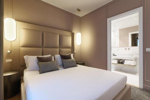 a bedroom with a large white bed and a bathroom at PRESTIGE BOUTIQUE APARTHOTEL - Piazza Duomo View in Milan