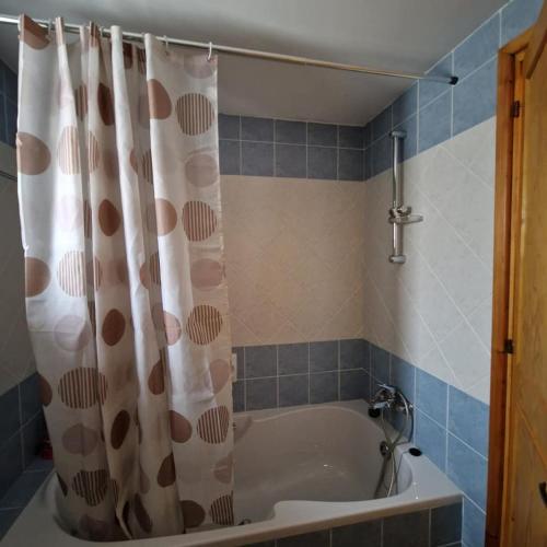 a bathroom with a tub with a shower curtain at THE ROCK HOUSE - Beautiful countryside with mandarins oranges and olive trees,. Near Limassol at Eptagonia village. in Ephtagonia