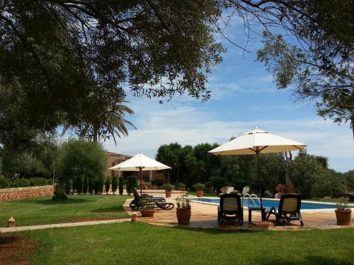 a patio with two umbrellas and a swimming pool at Agroturismo Finca Son Sala in Campos