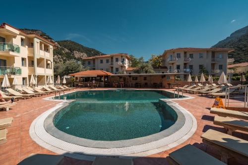 una piscina con tumbonas y un hotel en Belcehan Hotel en Oludeniz