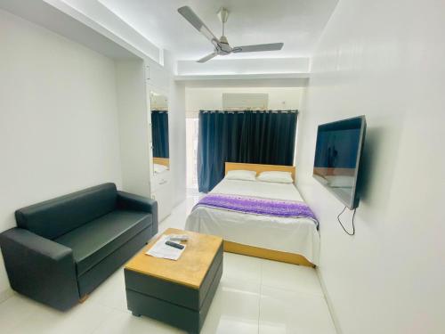 a bedroom with a bed and a chair and a couch at Studio apartment nearby Dhaka airport in Dhaka