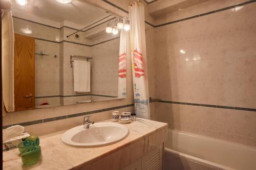 a bathroom with a sink and a mirror and a tub at Varandas do Oásis in Figueira da Foz