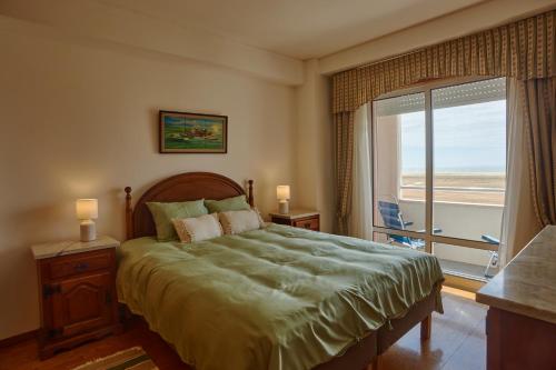 a bedroom with a large bed and a large window at Varandas do Oásis in Figueira da Foz