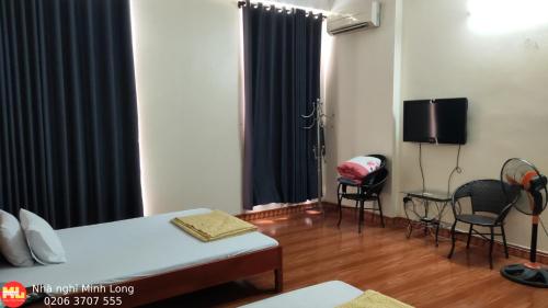 ein Schlafzimmer mit einem Bett, 2 Stühlen und einem TV in der Unterkunft NHÀ NGHỈ DU LỊCH MINH LONG - Quảng Trường in Cao Bằng