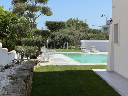 a swimming pool in a yard with chairs and grass at Al Mare da Francesca in Olbia