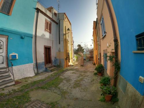 an alley with blue and white buildings and plants at Sole Azzurro Suite in Bosa