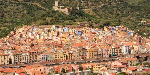 een grote stad met kleurrijke gebouwen op een heuvel bij Sole Azzurro Suite in Bosa