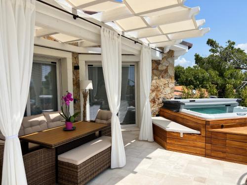 une terrasse avec un bain à remous et une table dans l'établissement Suite Villa Aquamarina con Jacuzzi Riservata, à Porto Pino
