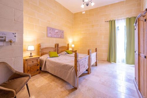 a bedroom with a bed and a chair at Tal-Andar Farmhouse in Kerċem