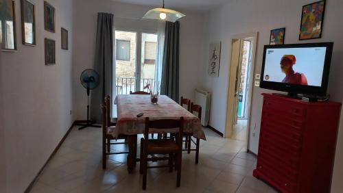 een eetkamer met een tafel en een flatscreen-tv bij Casa Martina "holiday home" Marano Lagunare in Marano Lagunare