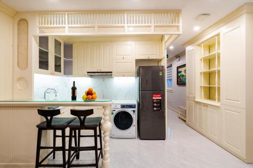 a kitchen with a refrigerator and two bar stools at Wild Lotus Hotel Apartment 2 in Hanoi