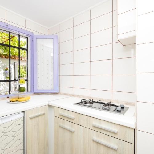 a white kitchen with a stove and a window at Apartments Dominik in Mali Lošinj