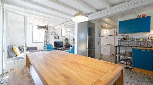 a kitchen and living room with a wooden table at Chalet de charme climatisé, son Jacuzzi - SPA privatif et la piscine de la Maison Bleue du Gers in Savignac-Mona