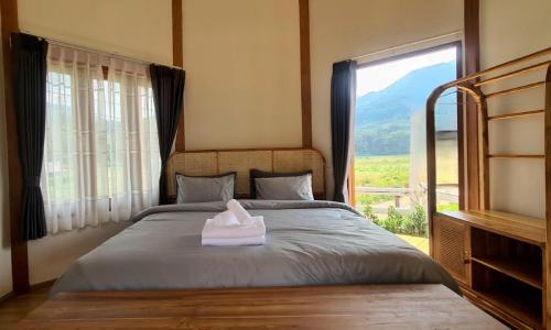 a bedroom with a bed with a large window at Times Klang Sapan Resort in Ban Sapan