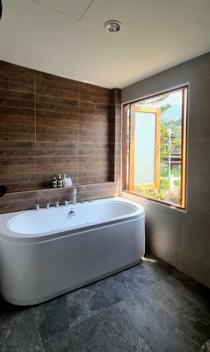 a large white tub in a bathroom with a window at Times Klang Sapan Resort in Ban Sapan