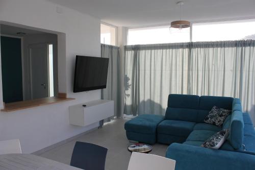sala de estar con sofá azul y TV en Isola Bianca, en Isola delle Femmine