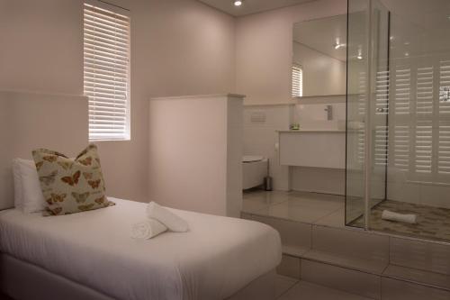 a bathroom with a bed and a glass shower at Beach Club Self Catering Apartments in Mossel Bay