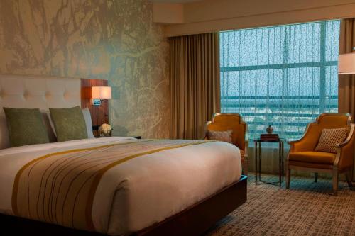 a bedroom with a large bed and a large window at Renaissance Baton Rouge Hotel in Baton Rouge