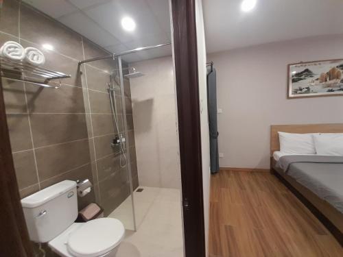 a bathroom with a toilet and a shower and a bed at Happy Home in Nha Trang
