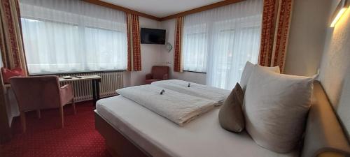 a hotel room with a bed with white pillows at Haus Tirol Appartements in Ried im Oberinntal