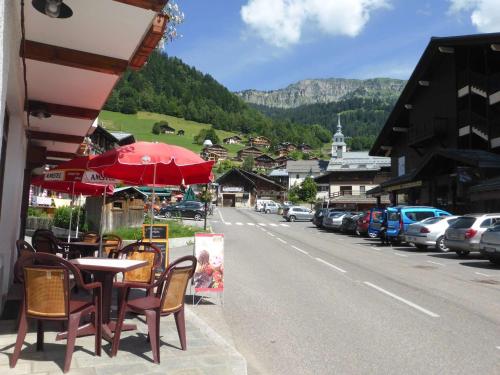 - une table avec des chaises et un parasol sur le côté de la rue dans l'établissement Studio Cosy au Cœur d'Arêches-Beaufort, Proche Pistes & Commerces, Idéal Couple + Enfant - FR-1-342-253, à Beaufort