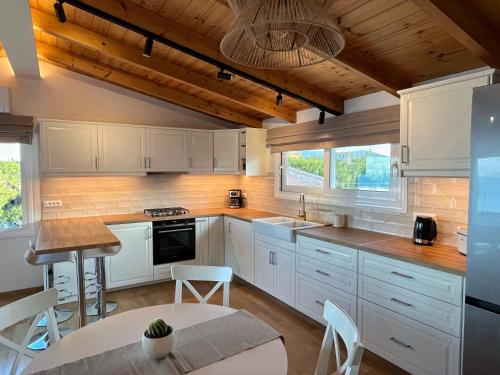 a kitchen with white cabinets and a table and chairs at Osservatorio House in Laganas