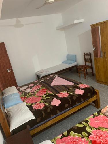 a bedroom with a bed with a flower patterned blanket at Shivalaya Homestay in Madikeri