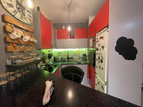a kitchen with red and green cabinets and a clock at Seaside apartment in Athens