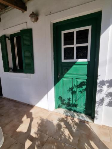 una puerta verde y una ventana en una pared blanca en Peyko Rooms, en Kerion