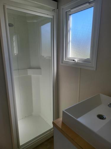 a bathroom with a shower and a sink and a window at camping Pradon in Arnuero