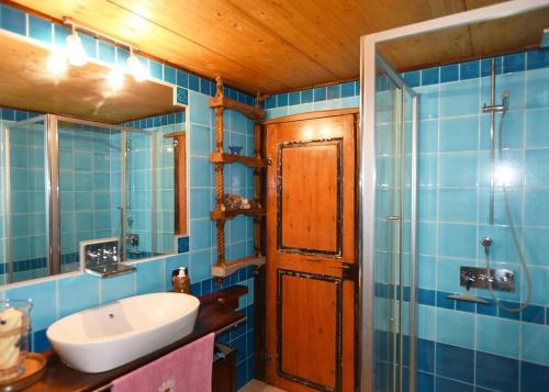 a blue tiled bathroom with a sink and a mirror at Splendida villa in riva al mare in Orosei