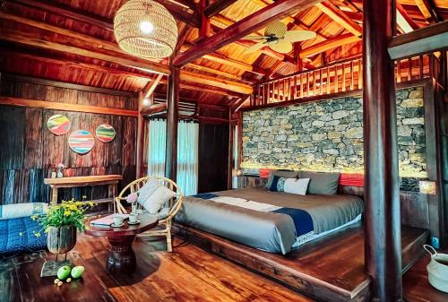 a bedroom with a bed and a stone wall at Natalie's Villa & Resort in Mộc Châu